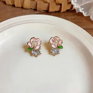 Gros plan de boucles d'oreilles fleurs roses avec cœurs en perles et gros cristaux.