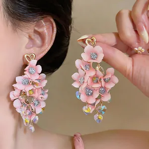 Detail view of pink fabric floral drop earrings with iridescent heart crystals.
