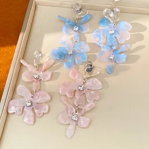 Close-up of elegant resin flower tassel earrings with heart studs and rhinestones