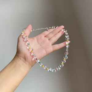 Clear heart-shaped beaded necklace with colorful accents held in hand, detail view.