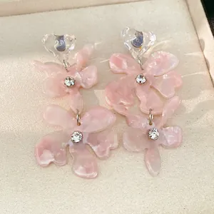 Close-up of pink resin flower earrings with sparkling rhinestones and heart detail.