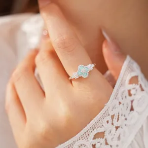 Silberner Zirkon-Kleeblatt-Ring am Finger mit einem Detail aus mintgrünen Sternen