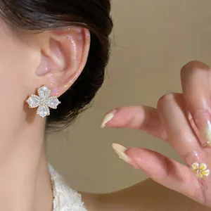 Close-up of elegant flower-shaped zircon earring with 18K gold plating on model
