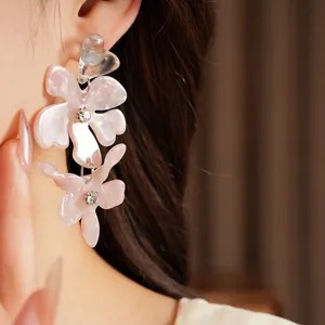 Detailed view of pale pink resin flower earrings with sparkling crystals worn on the ear