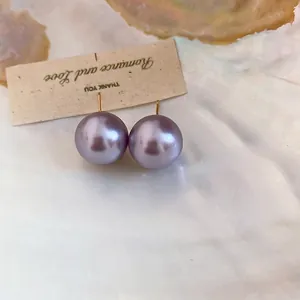 Elegant 18K gold plated large purple pearl stud earrings displayed on a shell background