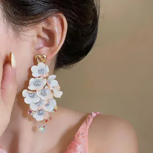 Close-up showing elegant fabric floral tassel earrings with gold heart studs on ear