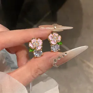 Détail macro de boucles d'oreilles fleurs roses élégantes avec gros cristaux et perle