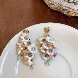 Close-up of elegant white fabric flower drop earrings with sparkling crystal heart studs