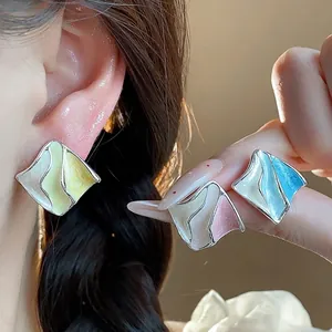Orecchini a perno geometrici smaltati con design a pieghe ondulate in giallo, rosa e blu.