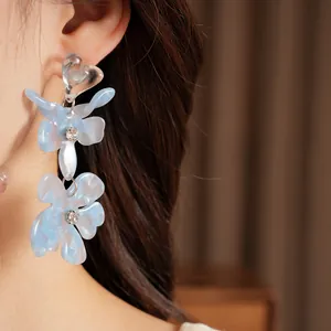 Close-up of light blue resin flower earrings with heart top and crystal center