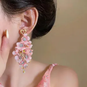 Detail view of pink fabric floral tassel earrings with heart-shaped gold studs.