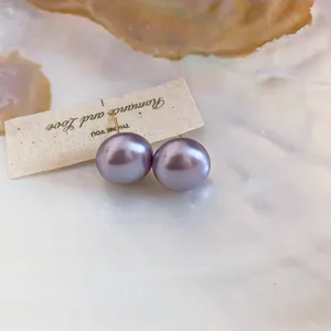 Macro view of elegant purple pearl stud earrings with 18K gold plating on shell base