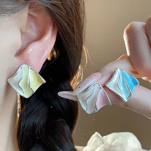 Dettaglio di orecchini a perno geometrici in smalto colorato con design pieghettato argento.