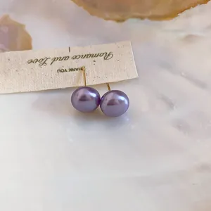 Close-up of lavender pearl stud earrings with 18K gold plated posts on a cream background