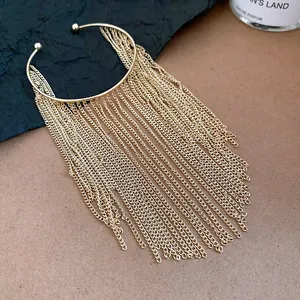 Detail view of a vintage gold metal cuff bracelet featuring long cascading chain tassels
