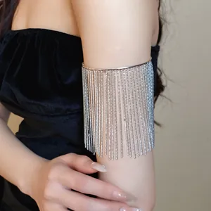 Detailed view of an elegant silver metal arm cuff with long chain tassels on a model