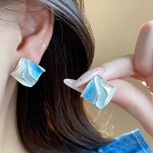 Vista dettagliata degli orecchini geometrici plissettati blu e bianchi su una modella