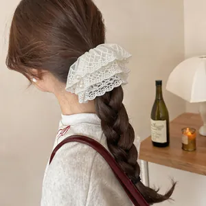 Elegantes Haargummi aus weißer Spitze mit Perlen in einer geflochtenen Frisur Detail