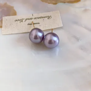 Elegant macro view of 18K gold plated stud earrings featuring round purple pearls.