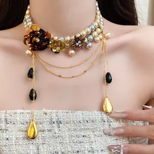 Gros plan d'un collier de perles multicouche style vintage avec breloques fleurs et gouttes.