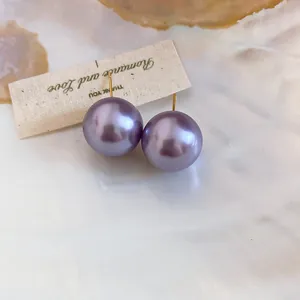 Elegant purple pearl stud earrings with 18K gold plating displayed on a shell background