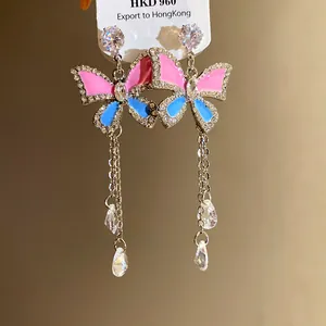 Detail view of butterfly earrings with pink and blue enamel and sparkling crystal tassels.
