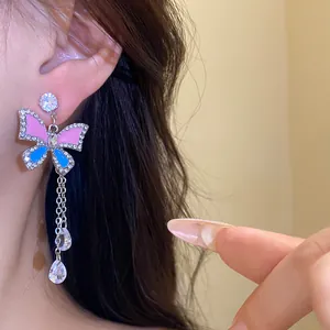 Close-up view of pink and blue butterfly earrings with rhinestone crystal tassels