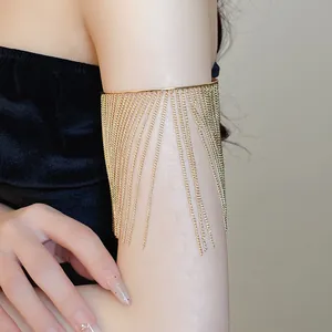 Detailed view of a stylish golden metal chain tassel arm cuff on a female model's arm