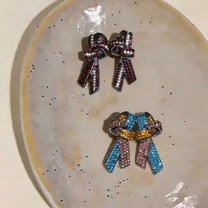 Vue détaillée de deux paires de boucles d'oreilles nœuds en cristal sur une assiette.