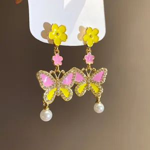 Close-up detail of colorful enamel butterfly and flower drop earrings with shiny crystals