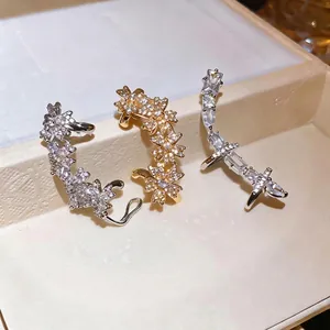 Bagues d'oreilles en zircon étincelant aux formes florales et géométriques sur un plateau beige