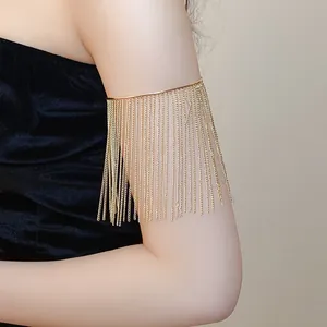Detail view of a gold metal tassel arm cuff bracelet on a model wearing black velvet