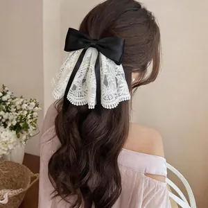 Detailansicht einer eleganten schwarzen Satinschleife mit weißer Spitze im Haar