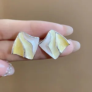 Primo piano dettagliato di orecchini geometrici plissettati con smalto giallo e bianco