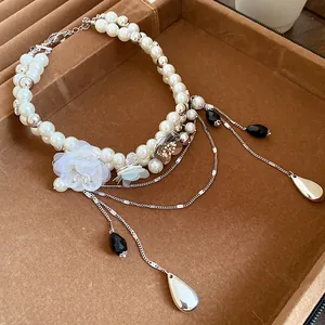 Gros plan d'un collier de perles vintage avec des charmes de fleurs et des glands