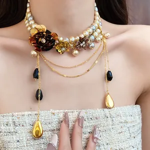 Gros plan d'un collier de perles vintage avec fleurs en métal et chaînes dorées.