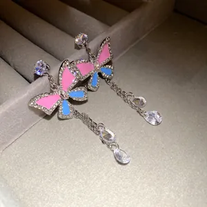 Close-up of butterfly earrings with color-block enamel and sparkling crystal tassels