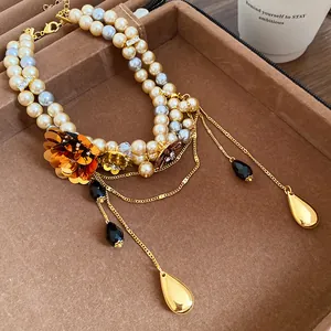 Détail d'un collier de perles vintage avec breloque fleur dorée et élégants pendentifs à pompons