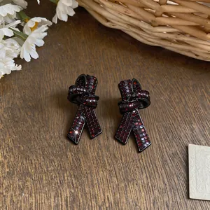 Gros plan de boucles d'oreilles nœuds en argent S925 avec strass rouge foncé.