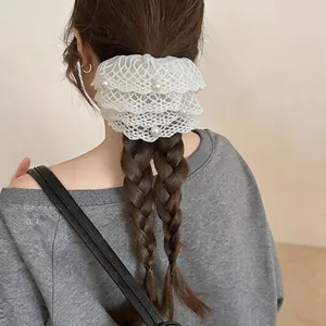 Detailansicht eines weißen Spitzen-Haargummis mit Perlen an einer geflochtenen Frisur