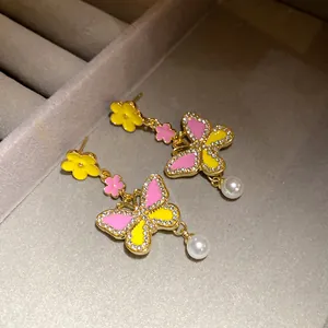 Detailed view of color-blocked butterfly earrings with rhinestones and pearl drops