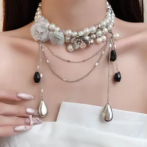 Détail d'un collier ras du cou en perles vintage avec fleurs et pendentifs en goutte