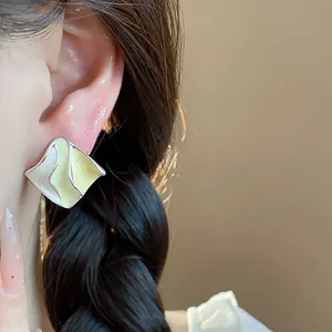 Primo piano di orecchini geometrici in smalto verde lime e crema con bordo ondulato