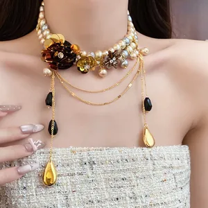 Détail d'un collier de perles vintage style palais avec fleurs en métal et pendentifs dorés