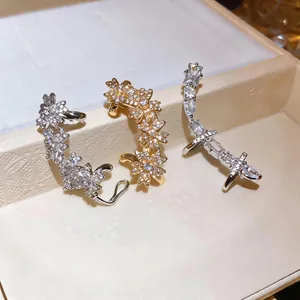 Détail de boucles d'oreilles ear cuffs en zircon fleur et géométriques sur plateau à bijoux