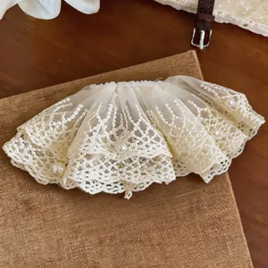 Elegante Haarklammer aus Spitze mit Perlenakzenten auf rustikalem Hintergrund.