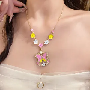 Close-up detail of a colorful enamel butterfly necklace with floral charms on a model