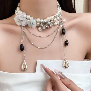 Détail d'un ras-de-cou en perles vintage avec breloques fleurs et pendentifs élégants en goutte.