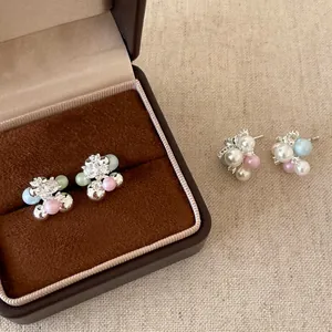Dettaglio macro di orecchini a perno a grappolo d'uva con accenti colorati e cristalli