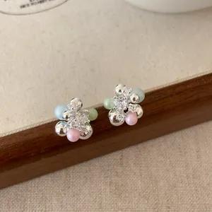 Dettaglio di orecchini a forma di uva in argento con perle colorate e pietre di zircone